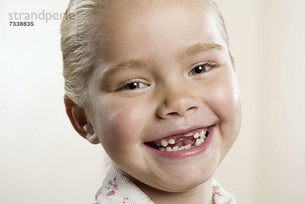Ein glückliches  junges Mädchen  dem die beiden Vorderzähne fehlen.
