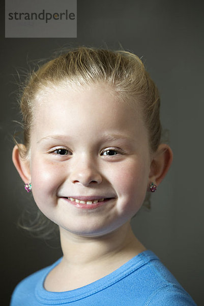 Ein lächelndes junges Mädchen mit Ohrringen.