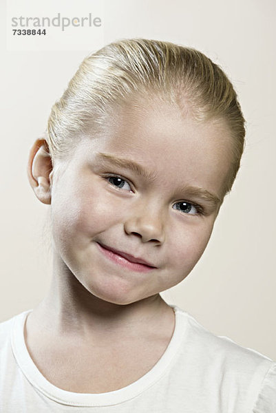 Ein junges Mädchen mit dem Kopf gespannt lächelnd.