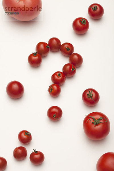 Kleine Tomaten zu einem Fragezeichen angeordnet  umgeben von unterschiedlich großen Tomaten