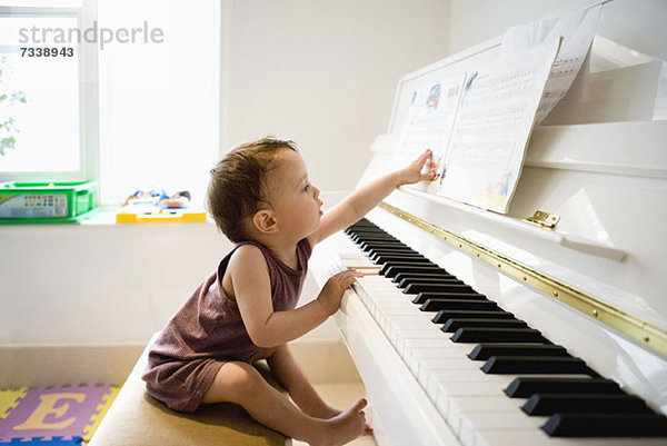 Ein kleiner Junge sitzt am Klavier und greift neugierig nach den Noten.