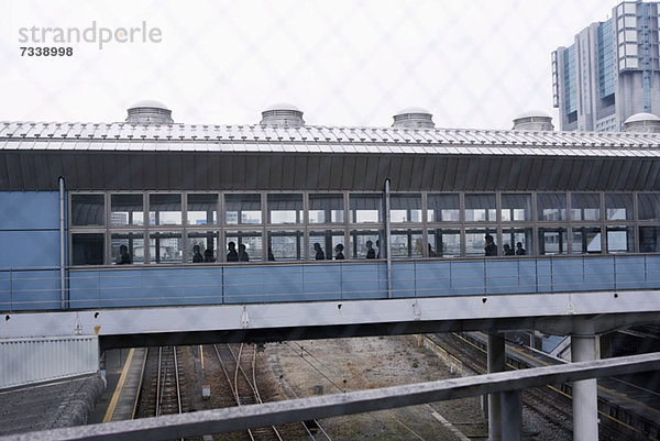 Bahnsteigbrücke durch einen verschwommenen Drahtgitterzaun gesehen