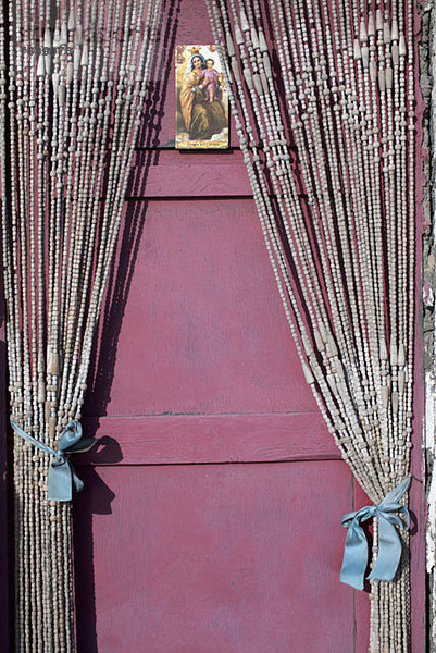 Eine heilige Karte mit der Jungfrau Maria und dem Jesuskind an einer Tür mit Perlenvorhängen.