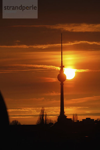 Der Fernsehturm am Alexanderplatz  der sich vor einem wunderschönen Himmel mit Sonnenuntergang abhebt.