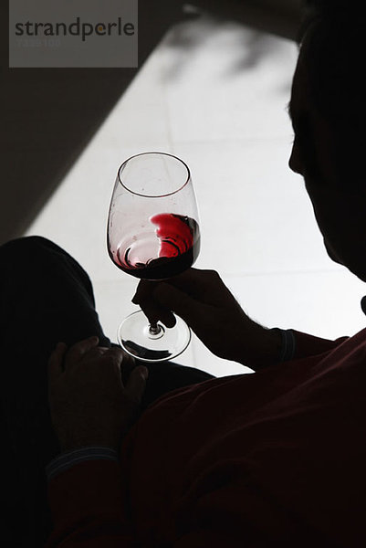 Eine Person mit Silhouette  die Wein in einem Weinglas wirbelt.