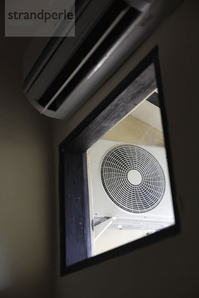 Ein elektrischer Ventilator durch ein Fenster gesehen  Blickwinkel niedrig