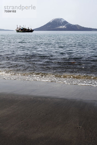 Wasserkante  Blick auf das vorbeifahrende Boot am Vulkan Krakatau  Indonesien