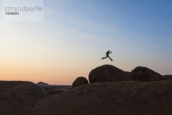 Junger Mann im Sprung  Granitfels  Spitzkoppegebiet  Damaraland  Namibia  Afrika