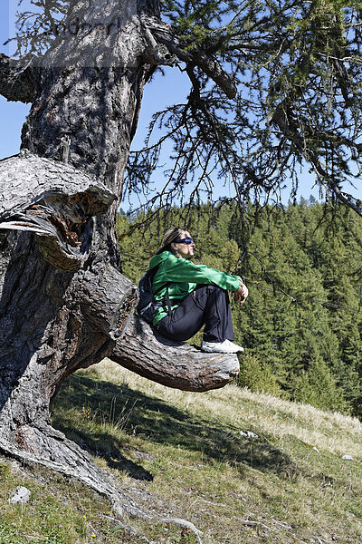 Wanderin sitzt auf abgesägtem Ast  Bürgeralm Aflenz  Bruck an der Mur  Steiermark  Österreich  Europa
