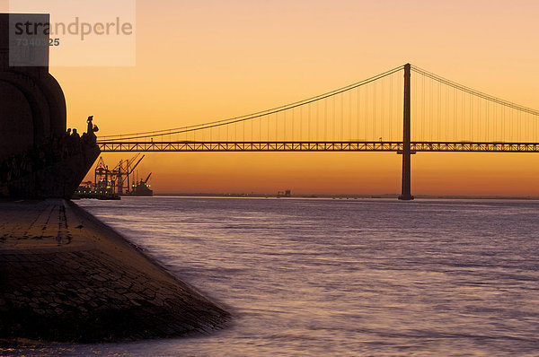 Brücke des 25. April  Ponte 25 de Abril  über den Tejo in der Morgendämmerung  mit dem Denkmal der Entdeckungen  Lissabon  Portugal  Europa