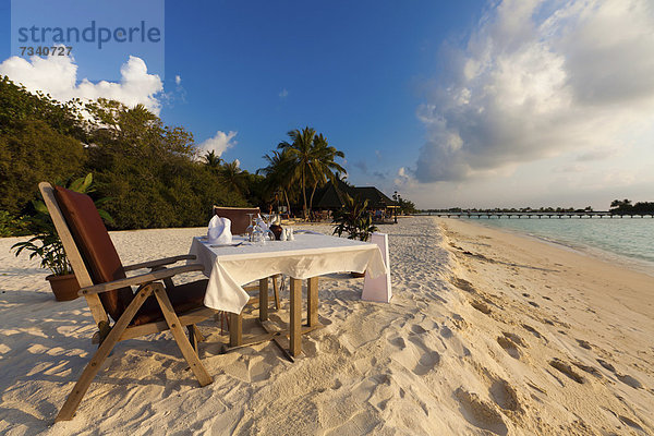 Ein Tisch ist am Strand für das Abendessen gedeckt  hinten Paradise Island  Lakanfinolhu  Nord-Male-Atoll  Republik Malediven  Indischer Ozean  Asien