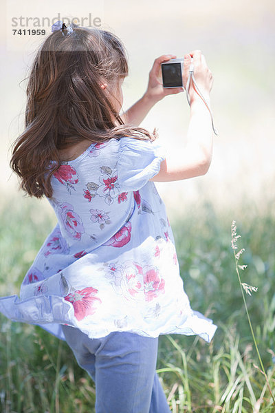 Mädchen beim Fotografieren im hohen Gras