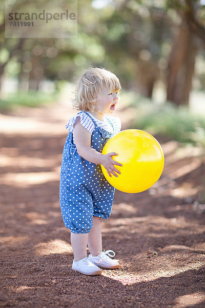 Kleinkind Mädchen mit Ball auf Schotterpiste