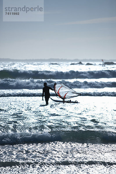 Mann mit Windsegelbrett in Wellen