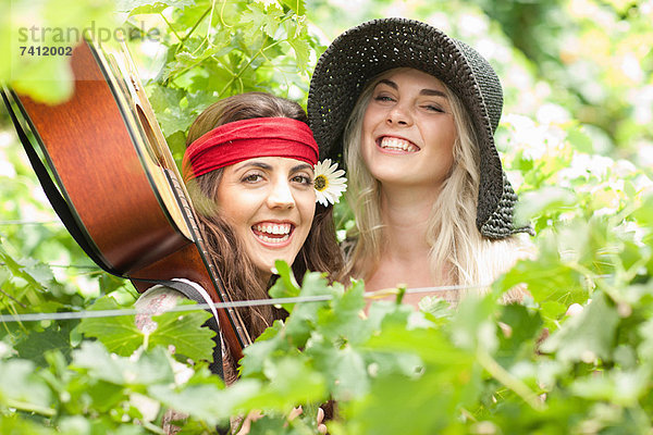 Frauen halten guitar†in hohe Pflanzen