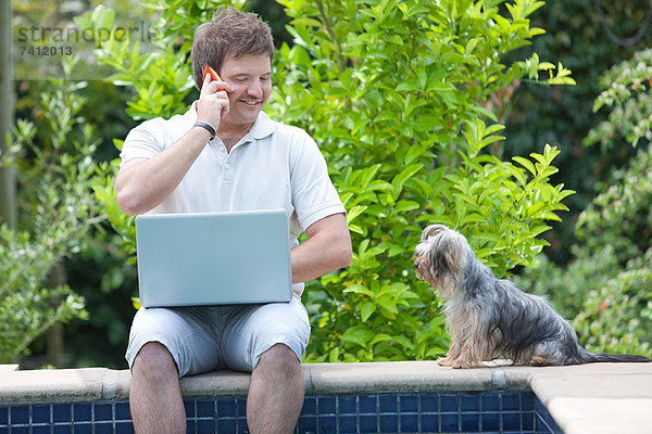 Mann mit Handy und Laptop im Freien