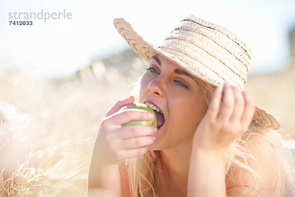 Frau isst Apfel im hohen Gras