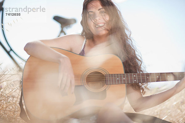 Frau spielt Gitarre im hohen Gras