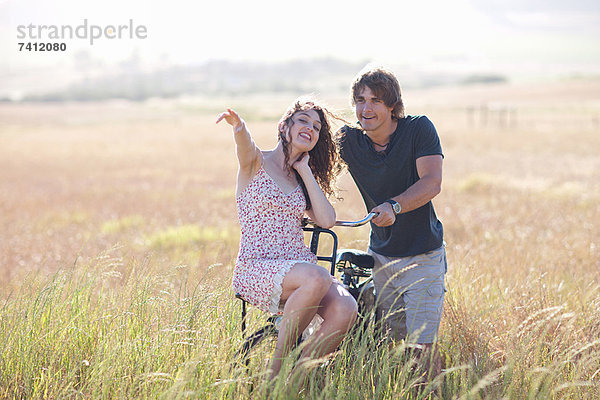 Paar spielt auf dem Fahrrad im hohen Gras