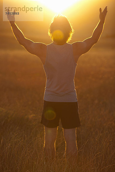 Mann steht im Feld bei Sonnenuntergang