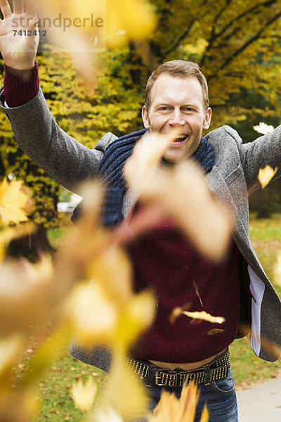 Mann spielt im Herbstlaub