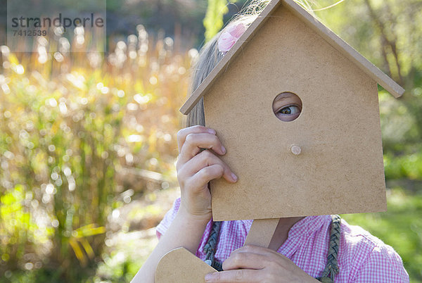 Mädchen schaut durchs Vogelhaus