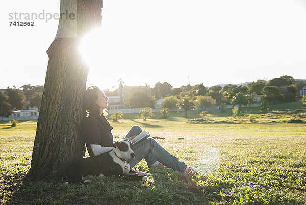 Frau entspannt sich mit Hund im Park