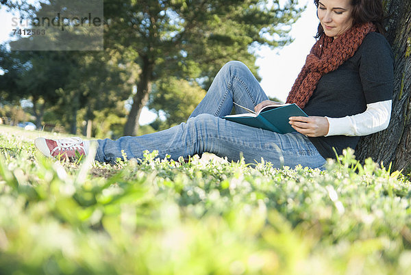 Frau liest Buch im Gras