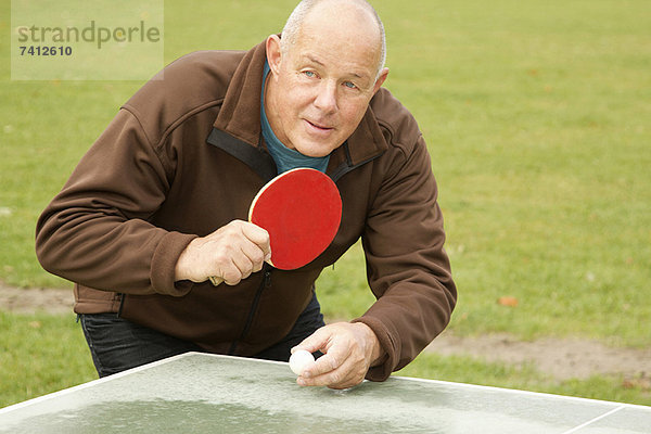 Älterer Mann beim Tischtennisspielen im Freien