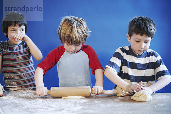 Jungen rollen Teig mit Nadeln aus.