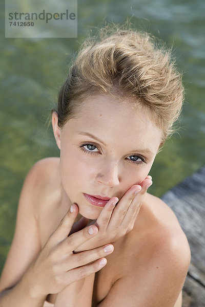 Frau sitzend am stillen See