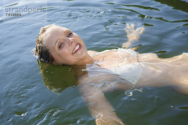 Lächelnde Frau schwebt im stillen See