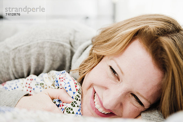 Lächelnde Frau auf dem Bett liegend