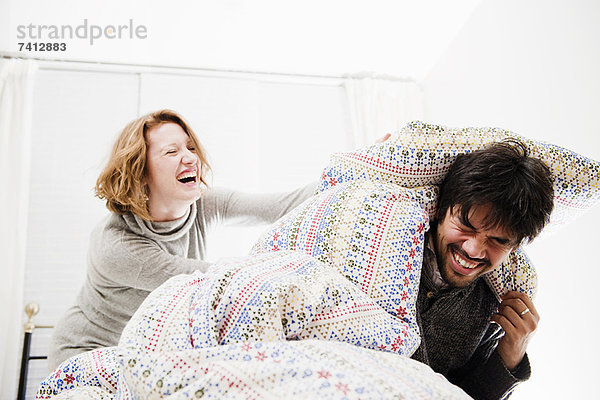 Lächelndes Paar spielt im Bett