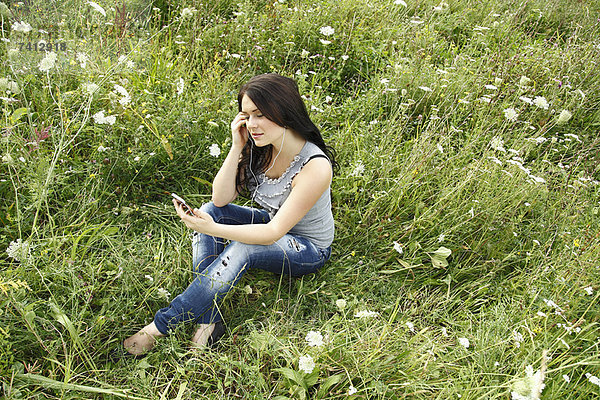 Frau hört Kopfhörer im Gras