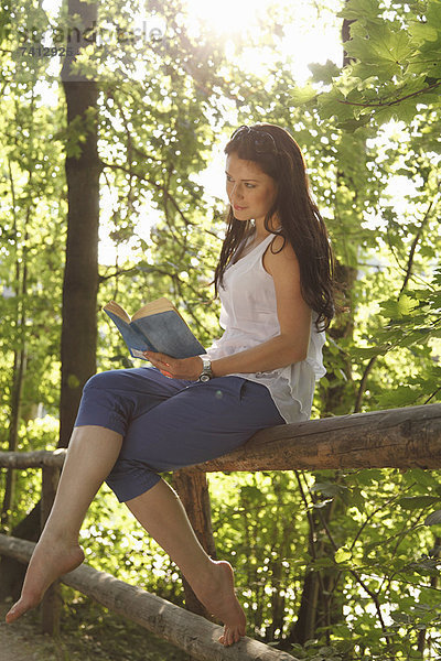 Frau liest Buch im Wald