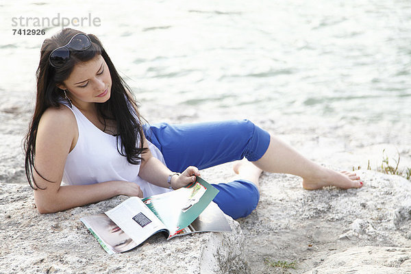 Frau liest Magazin am Strand