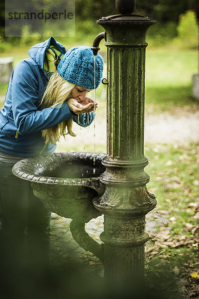 Frau trinkt aus Wasserfontäne