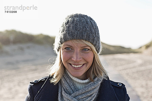 Lächelnde Frau beim Spaziergang am Strand