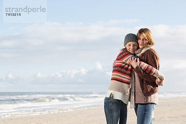 Lächelnde Frauen  die sich am Strand umarmen