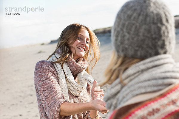 Lächelnde Frauen spielen am Strand