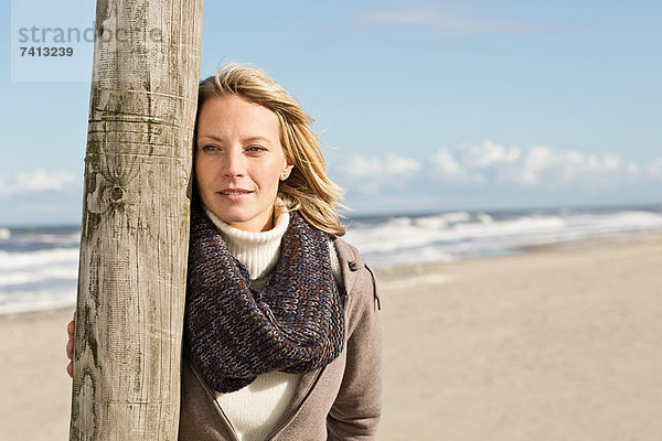 Frau lehnt sich an die Stange am Strand