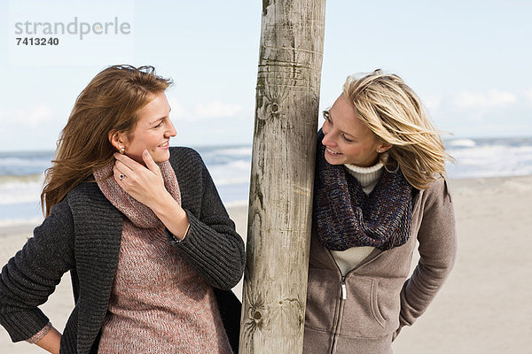 Lächelnde Frauen sprechen am Strand