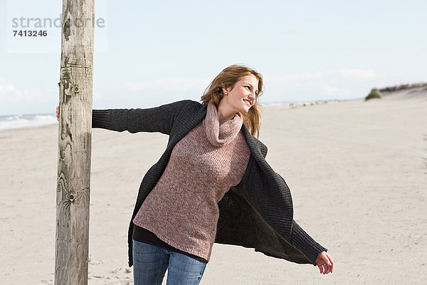 Frau schwingt von der Stange am Strand