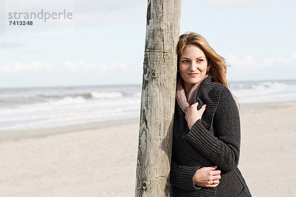 Frau lehnt sich an die Stange am Strand