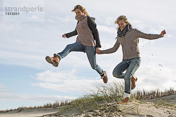 Lächelnde Frauen beim Laufen am Strand