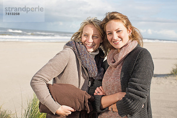 Lächelnde Frauen stehen am Strand