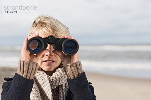 Frau mit Fernglas am Strand