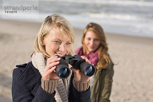 Frau mit Fernglas am Strand