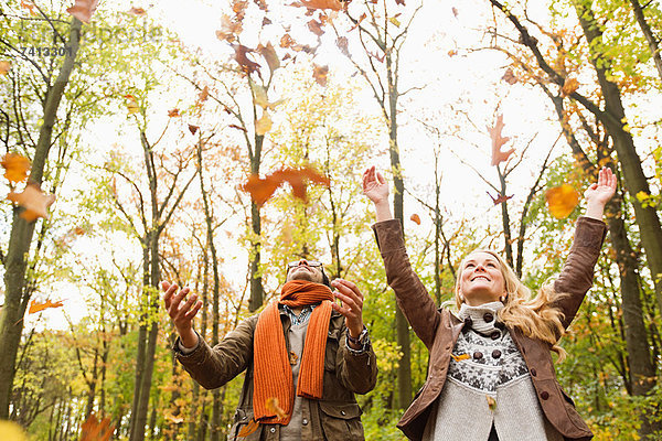 Lächelndes Paar spielt im Herbstlaub